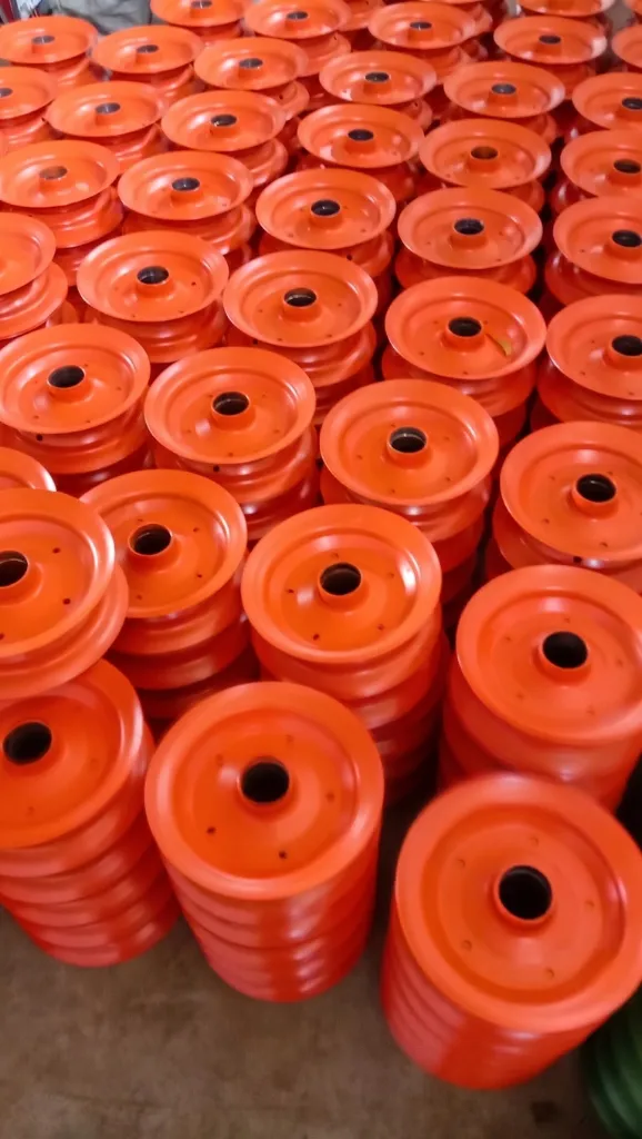 SYK factory floor showing mass production stacks of orange powder coated wheel discs