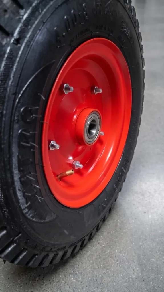 Close up view of red wheel disc assembly showing tyre tread and brass inflation valve stem